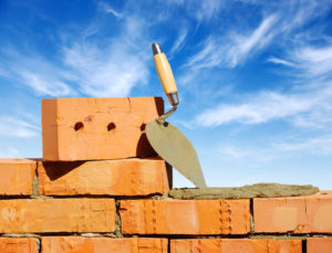 brick wall partially built with tool against blue sky