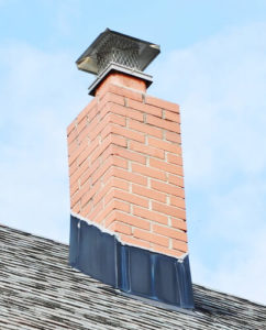 chimney with black flashing and cap against blue sky